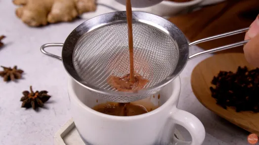 Cocoa tea mixture being strained into a mug
