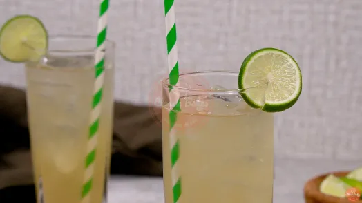 2 highball glasses filled with lime juice, garnished with a lime slice and green straws sticking out