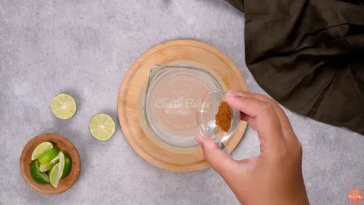 Brown cane sugar being added to the jug of lime juice