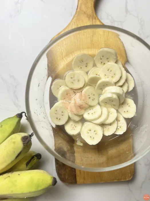 Sliced unriped bananas in a bowl soaking in lemon juice