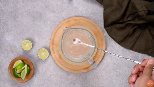 A teaspoon of lime juice being scooped out of the jug