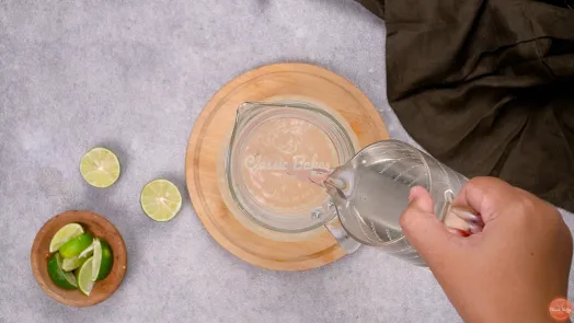 Water being poured into a jug of lime juice