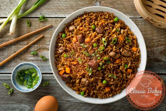 Aerial shot of Beef Fried Rice in a serving plate with chopsticks and scallions on the side
