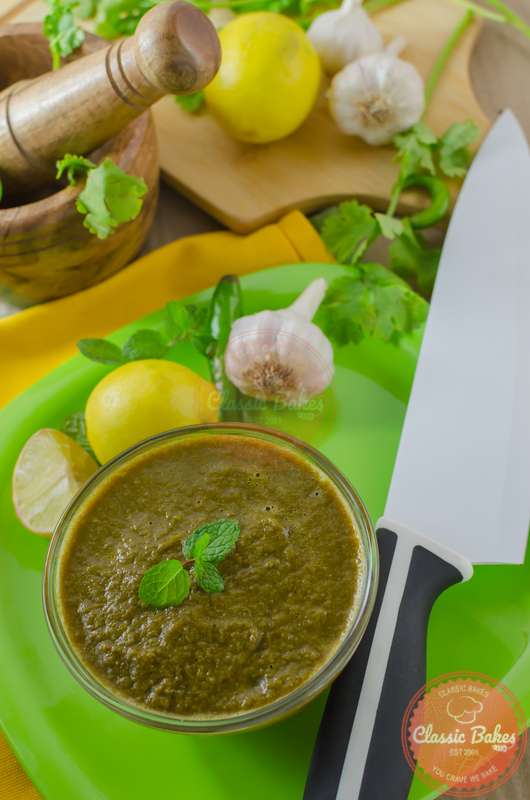 Cilantro Chutney in a bowl with ingredients and kitchen knife on the side