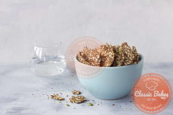 Front shot of Keto Seed Crackers in a bowl with a glass of water at the background
