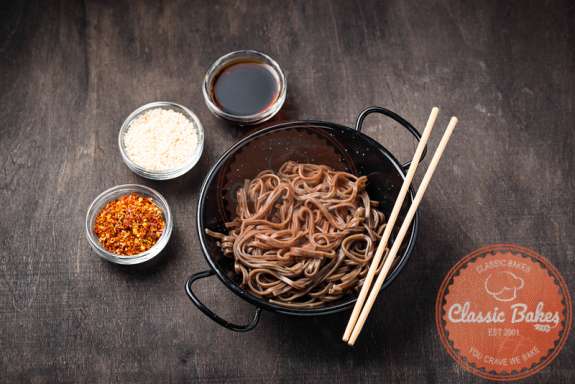 Aerial shot of Sesame Soba Noodles with condiments and chopsticks on the side