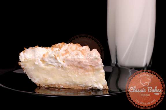 Slice of Homemade Coconut Cream Pie in a plate with a cup of milk at the background
