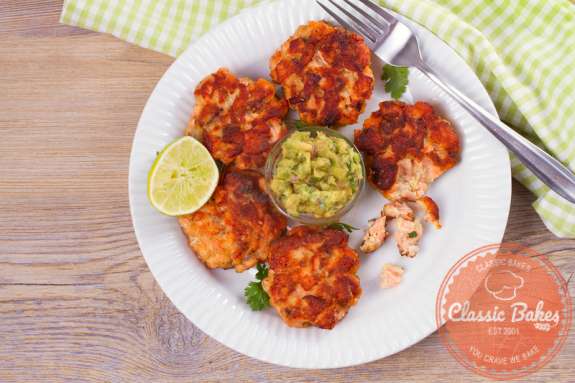 Aerial shot of Keto Salmon Cakes in a plate with guacamole dip and lime on the side