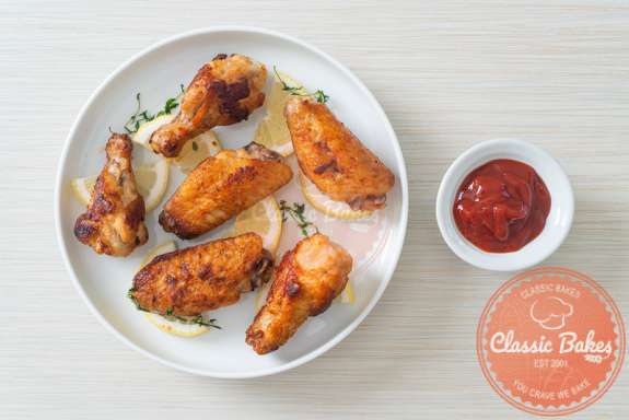 Aerial shot of Fried lemon pepper chicken wings in a plate with ketchup on the side