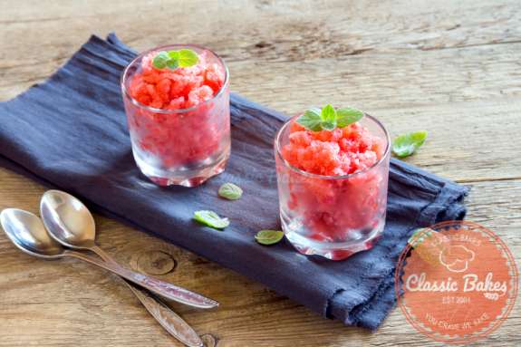 Front shot of two glasses of Fresh Strawberry Granita on top of blue cloth