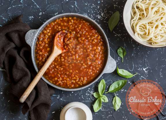Aerial shot of Lentil Bolognese in a pot with wooden spoon