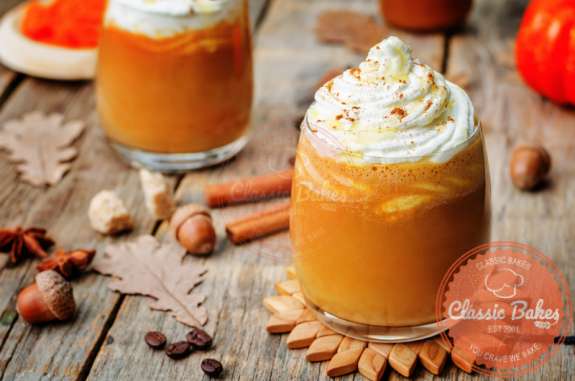 Front shot of Pumpkin Spice Latte Iced in a glass with acorns and cinnamon on the side