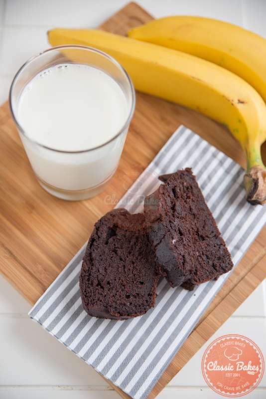 Aerial shot of sliced Vegan Chocolate Banana Bread with milk and banana on the side