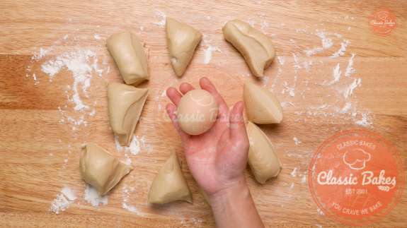 10 small pieces of dough being rolled on a floured countertop 