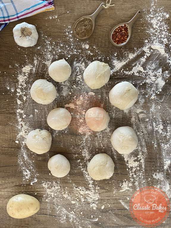 12 small balls of dough on a floured countertop 