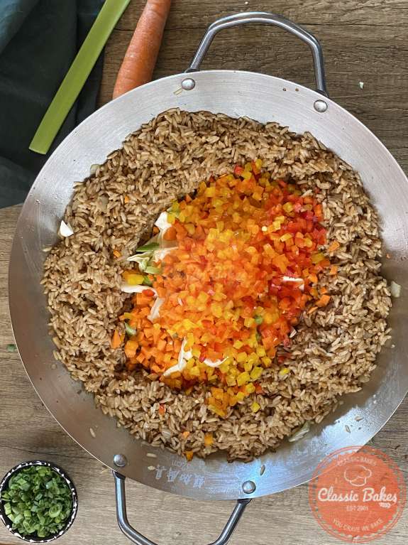 Aerial shot of rice coated in soy sauce with diced vegetables in the center