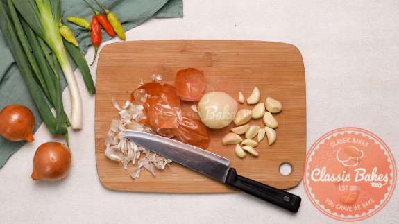 Arial view of a cutting board with a knife tomatoes chopped onions and garlic