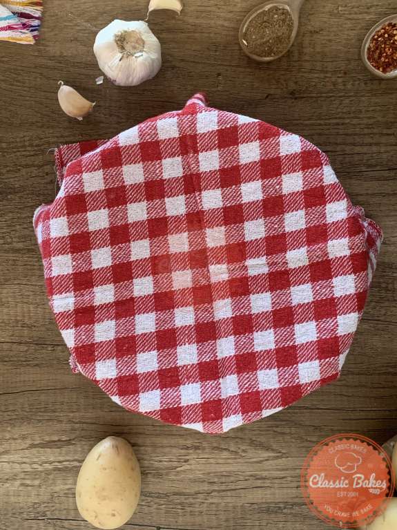 A bowl covered with a checkered kitchen towel