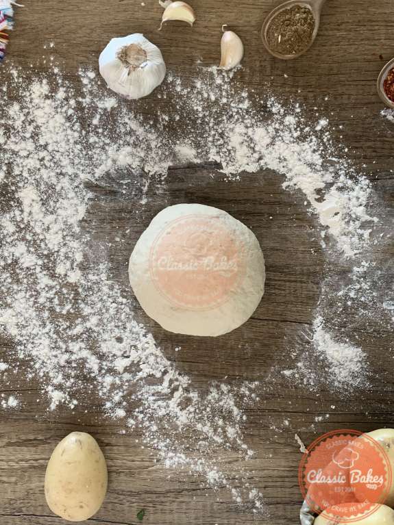 A bowl of dough on a countertop with flour sprinkled around it 