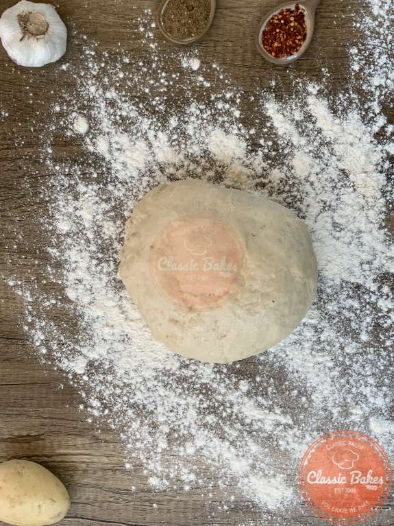 A bowl of dough on a countertop with flour sprinkled around it 