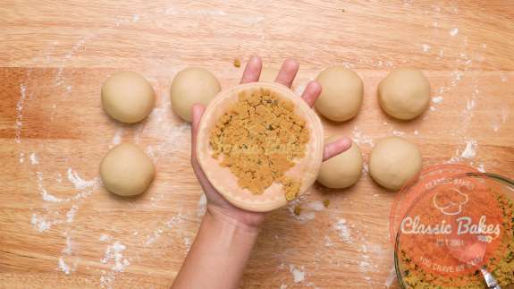 Circle of dough being held in a hand with dhal being added to it 