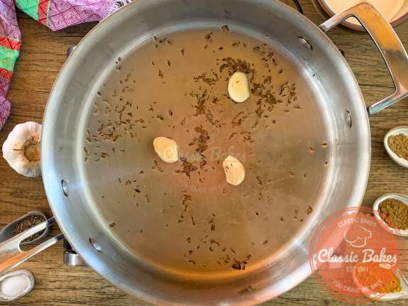 Cloves of garlic and spices cooking in a pot 