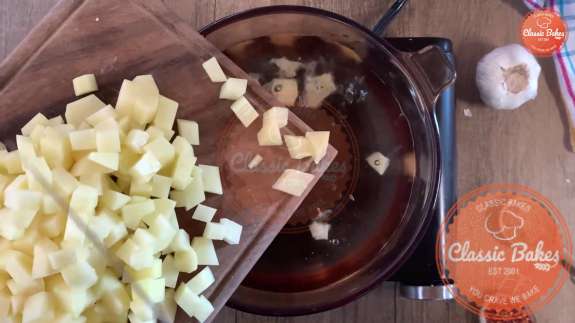 Diced potatoes being added to a pot of water 