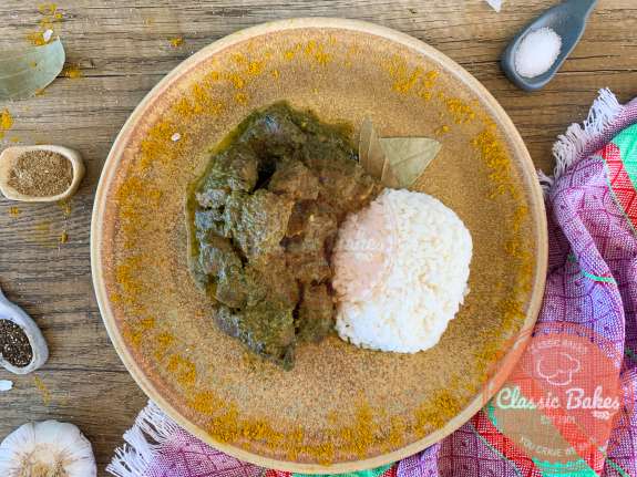 Dinner plate with curry goat and rice on a countertop 