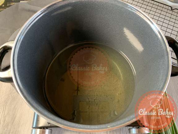 Large pot with oil being heated up on a stovetop 