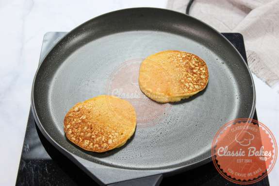 Overview of a greased pan with two pancakes flipped over