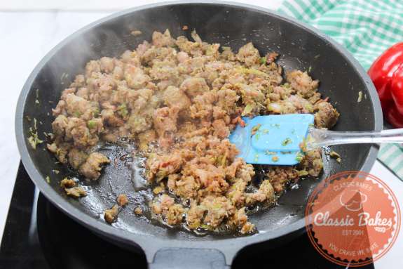 Overview of a pan containing cooked sausage onions and garlic 