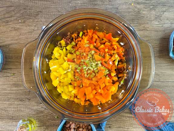 A pot with carrots, celery and bell peppers on top  