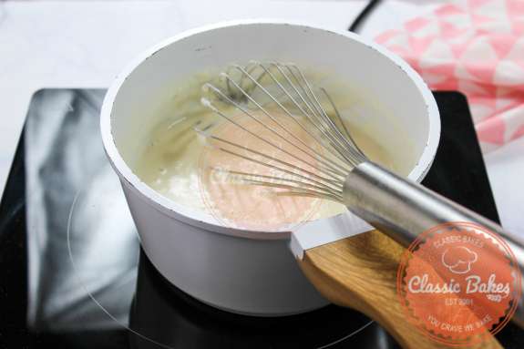 A saucepan with thickened coconut milk and a whisk 