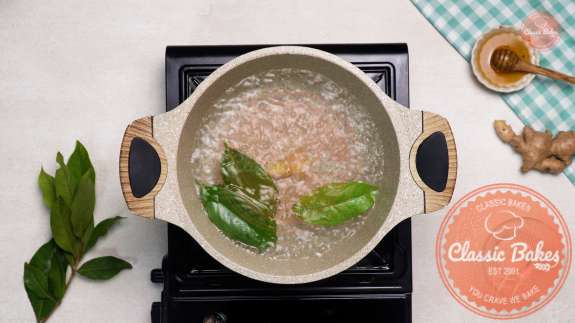 Arial of a pot of water with bay leaves and ginger inside 