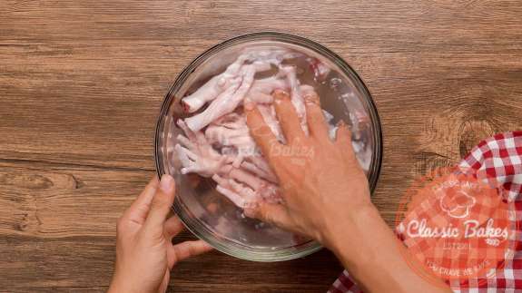 A bowl of chicken feet being washed in a glass bowl 