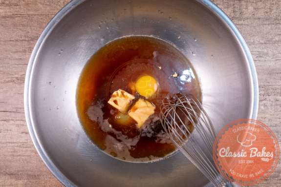 butter, stout, eggs and flavorings being mixed with a whisk in a bowl 