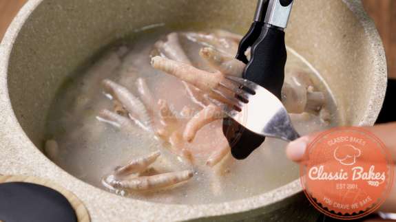 Chicken feet being checked for doneness with a fork 