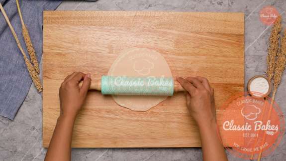 A circle of dough being rolled with a rolling pin 