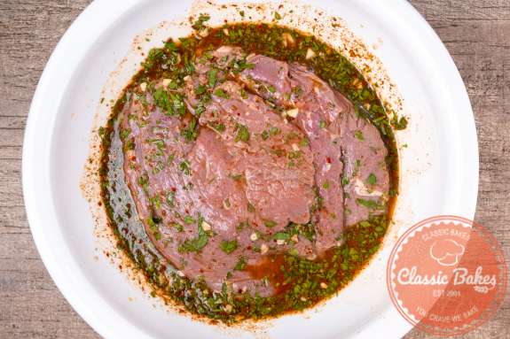 Flank steak marinating in a bowl 