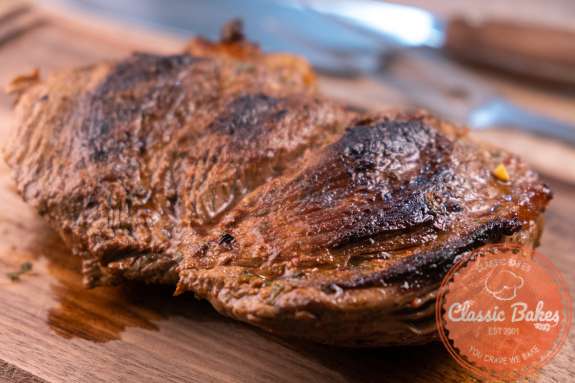 Flank steak resting on a wooden cutting board 