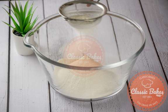 Flour being sifted into a glass bowl 