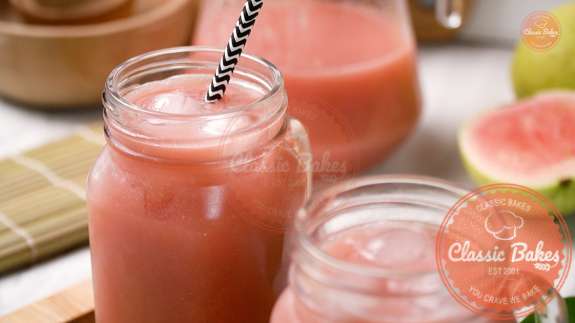 Glasses filled with ice and guava juice with a straw inside the glass 