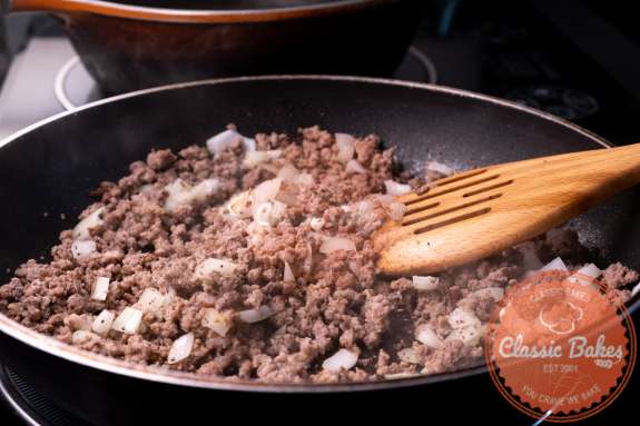 Ground beef onions and seasoning being cooked in a pan 