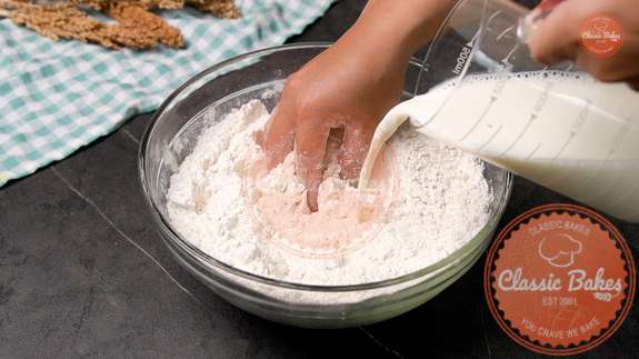 Milk being added to dough kneading in a glass bowl 