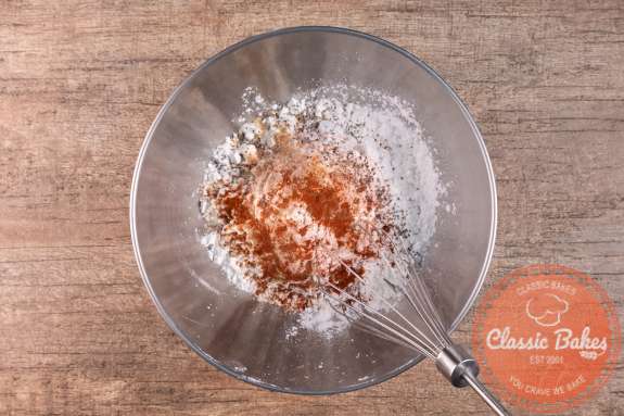 Overview of a bowl of flour with spices being whisked into it 