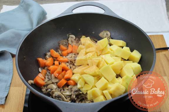 Overview of a skillet containing diced carrots and potatoes 