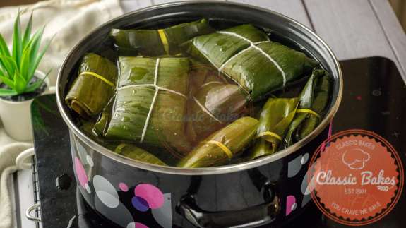 Paime wrapped in banana leaves boiling in a pot of water 