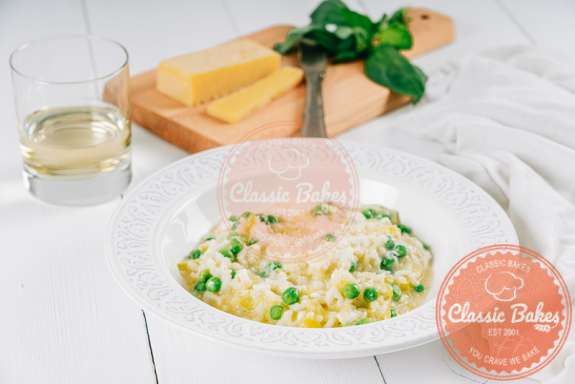 Sideview of a bowl of pea risotto with a cutting board in the background 