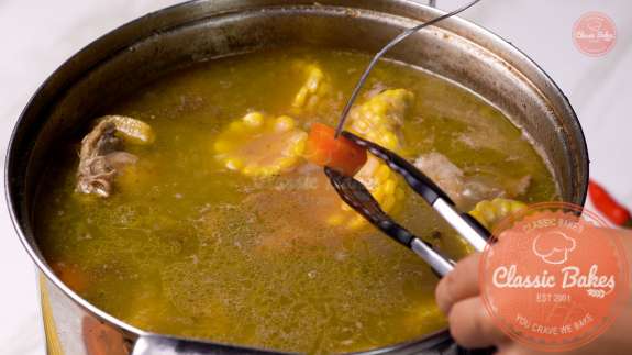 Pot of Sancocho with a fork above piercing a carrot 