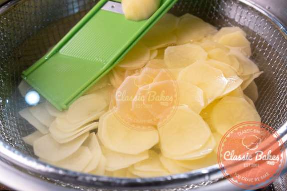 Potatoes being sliced into a bowl of water 